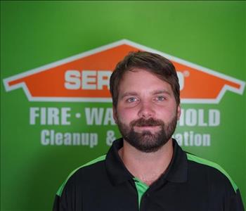 Man in front of green wall with orange SERVPRO logo.