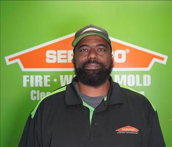 Man in front of green wall with orange SERVPRO logo.