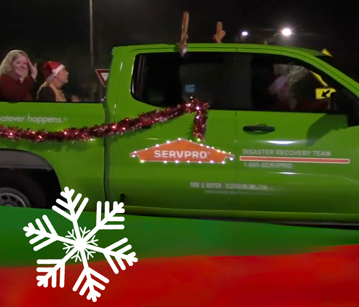 Servpro vehicle decorated with lights and antlers with empoyees waiving in the back of the truck